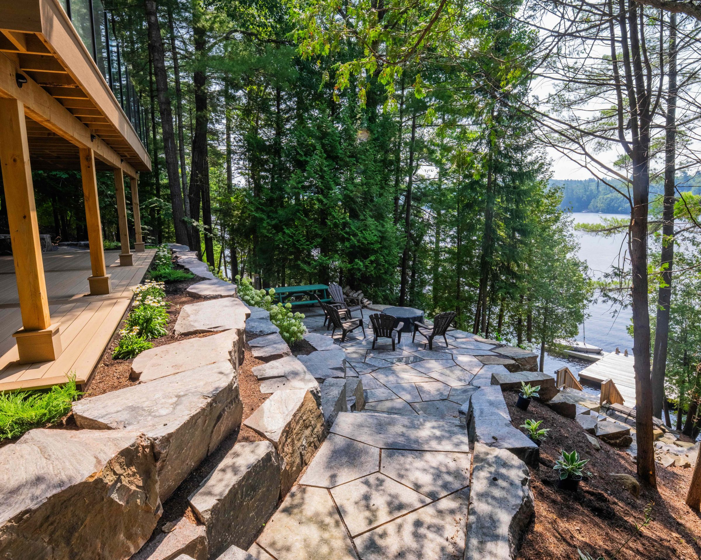 Natural granite flagstone patio and heavy armour stone retaining wall overlooking a Muskoka lake shoreline.