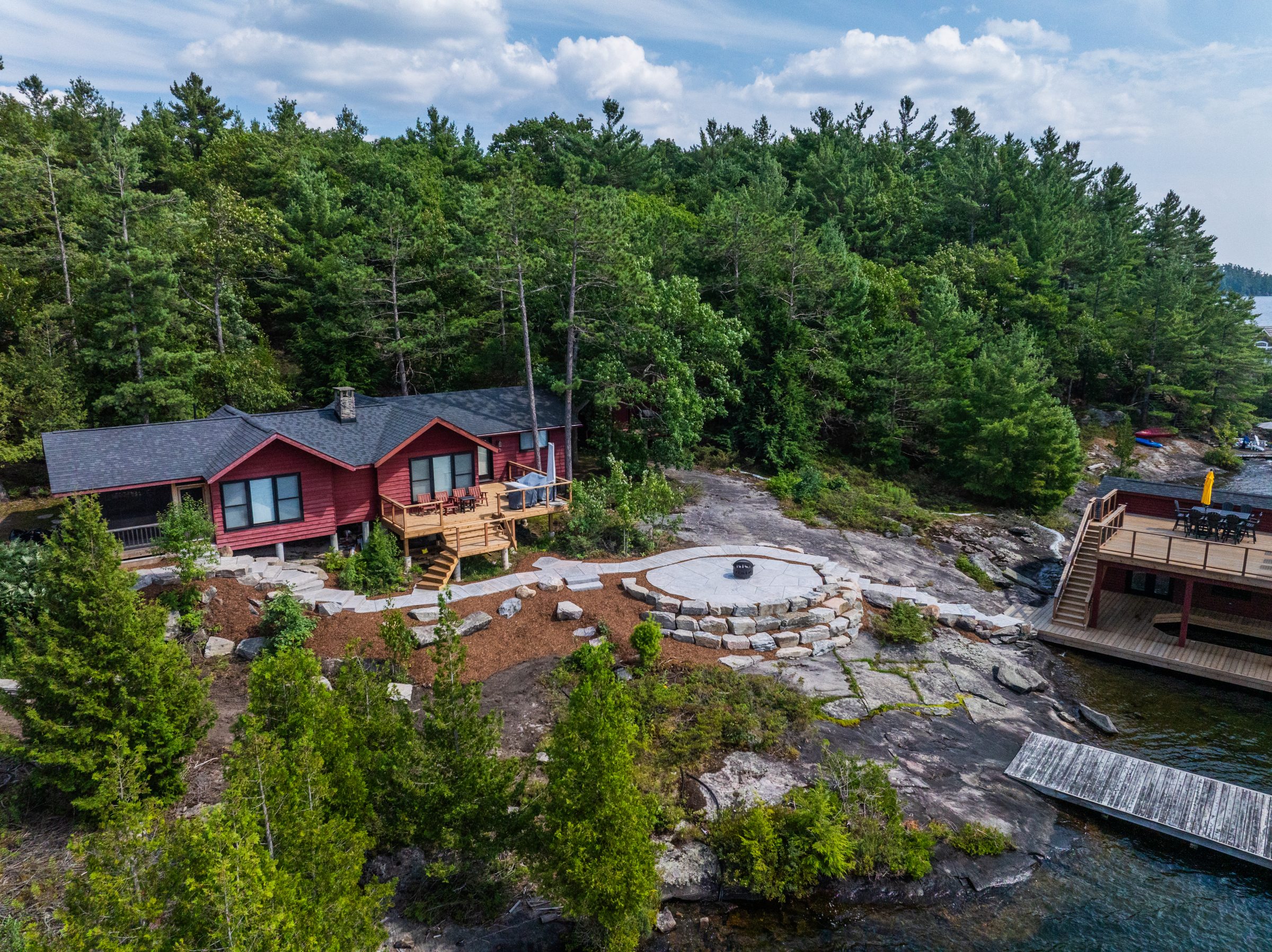 Custom natural stone patio installation on a rugged, sloped lakefront property in Muskoka.